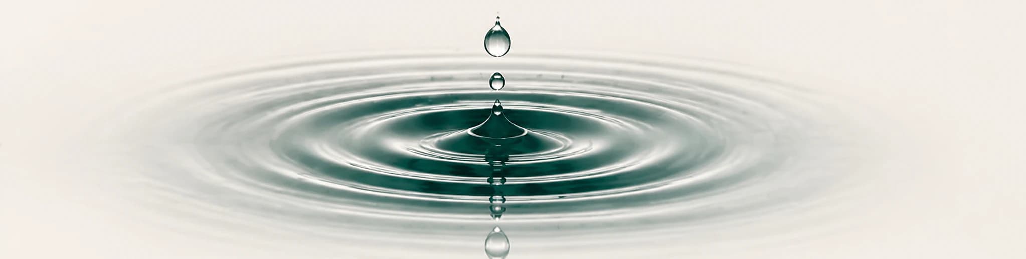 A water drop creating ripples on a still surface.